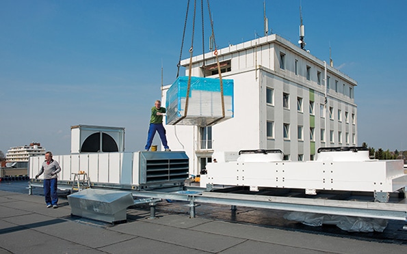 Wohngebäude mit Bauarbeitern und Kranlast im Vordergrund